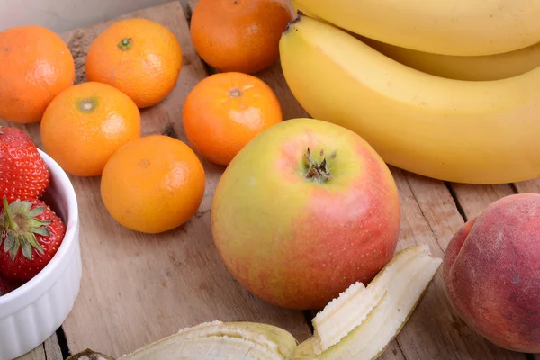 Banane mela mandarino fragola di pesca su sfondo di legno come concetto di cibo sano — Foto Stock