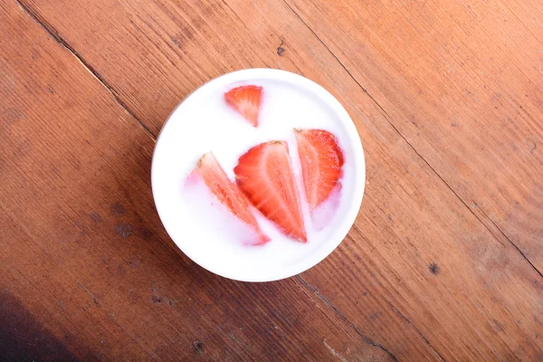 Tranche de tarte avec fraise sur assiette blanche, boisson au lait, fond en bois. Vue du dessus — Photo