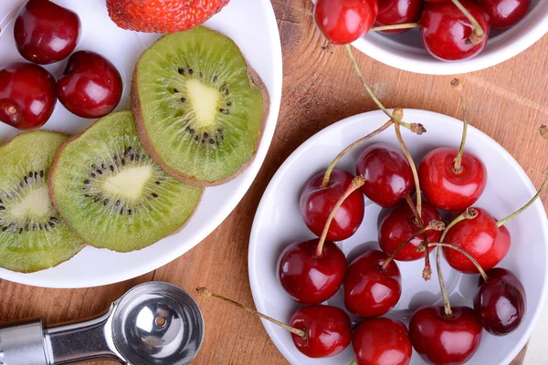 Fruit met kersen, aardbei, kiwi op houten plaat — Stockfoto