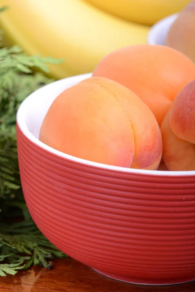 Bananas and apricots on red plate, close up — Stock Photo, Image