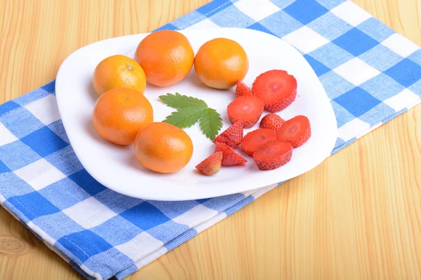 Una fetta di fragola rossa su piatto bianco con fette di mandarino e fragola — Foto Stock