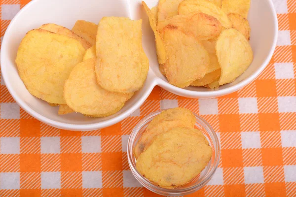 Chips und geschälte Kartoffeln auf einem weißen Teller — Stockfoto