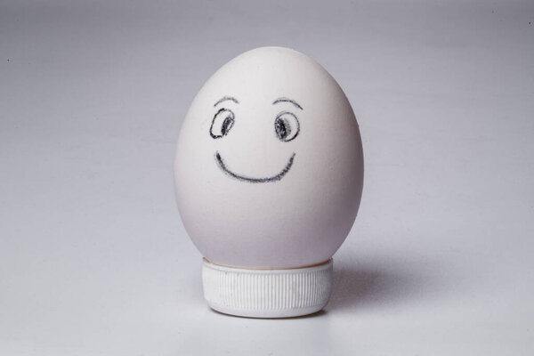 Chicken egg with a smiley face on a neutral white background.