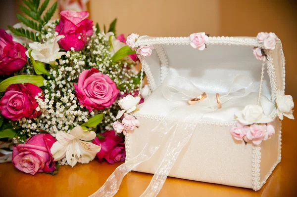 Anéis de casamento no porta-malas ao lado da noiva do buquê de casamento — Fotografia de Stock