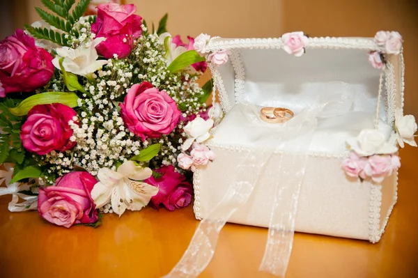 Wedding rings in the trunk next to the wedding bouquet bride — Stock Photo, Image