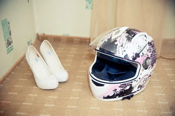 Pink motorcycle helmet and women's shoes lie on the floor — Stock Photo, Image
