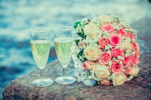 Glass of champagne and a bouquet of the bride on a background of water — Stock Photo, Image