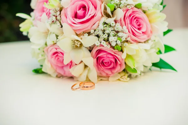 Anéis de casamento em um fundo branco com um buquê de fitas azuis — Fotografia de Stock