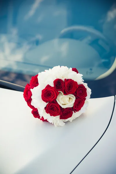 Svatební kytice ležící na kapotě auta — Stock fotografie