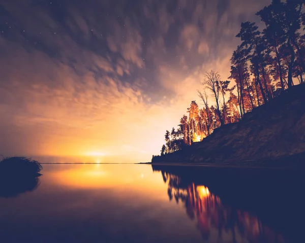 Cielo nocturno místico sobre un agua tranquila con siluetas de árboles. Mar de Kiev, Lyutizh, Ucrania. Imágenes de stock libres de derechos