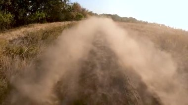 Toprak yolda yavaş çekimde giden bir araba. Bir arabanın tozu.
