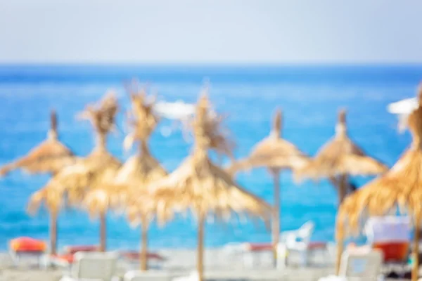 Spiaggia sfocata con ombrelloni di paglia — Foto Stock