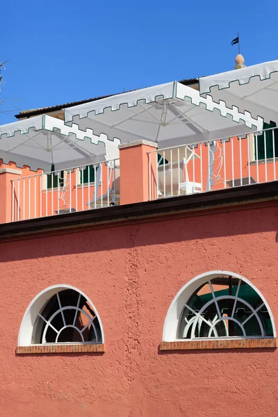 Edifício vermelho com guarda-chuvas brancos — Fotografia de Stock