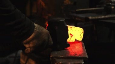 Yakından, bir demirci kızgın bir metale çekiçle vuruyor..