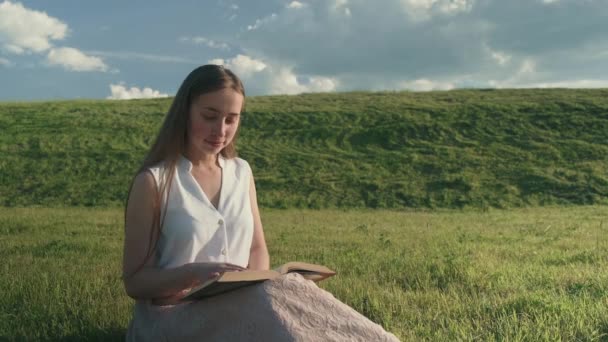 草地上的女孩屏息看书 — 图库视频影像