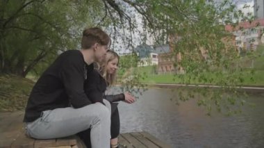 Couple sitting on a wooden pier and looking at the water