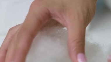 Kız elleriyle şehvetli beyaz kabarıklığa dokunuyor.