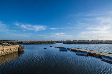 Mavi gökyüzünün altında, bataklıktaki iskelenin yanında bir tekne.