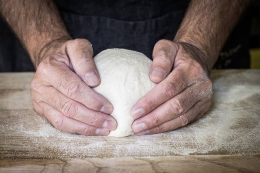 Pizzacı ahşap yüzeyde pizza için hamur hazırlıyor.