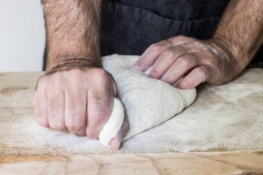 Pizzacı ahşap yüzeyde pizza için hamur hazırlıyor.