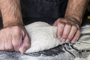 Pizzacı ahşap yüzeyde pizza için hamur hazırlıyor.