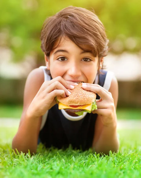 Adolescente chico comer hamburguesa al aire libre — Foto de Stock