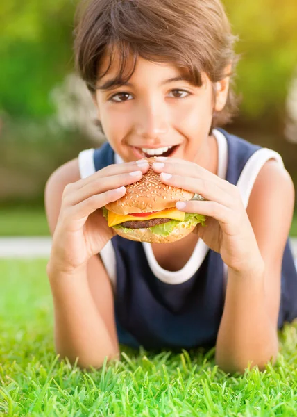 Menino feliz comer hambúrguer — Fotografia de Stock