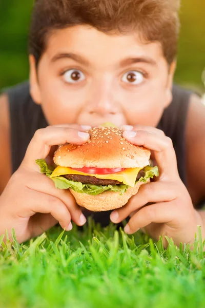 ハンバーガーを食べる空腹の少年 — ストック写真