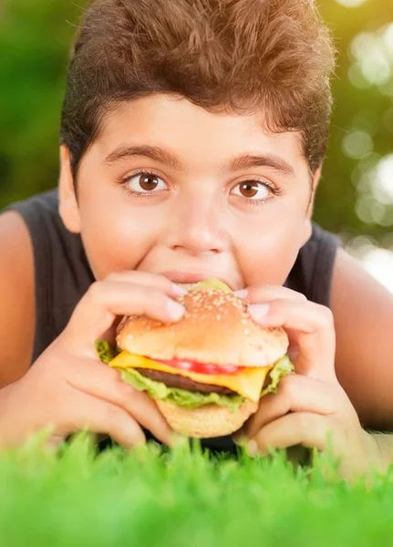 Aç çocuk burger yiyen — Stok fotoğraf