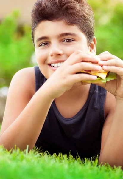 ハンバーガーを食べて幸せな少年 — ストック写真