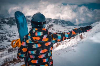 Female Snowboardcu 'nun Arka Manzarası Yükselmiş Elle Karlı Dağlar' ın Harika Manzarasının keyfini çıkarıyor. Aktif Sağlıklı Yaşam Tarzı. Kış Tatillerini Kayak Tatilinde Geçirmek
