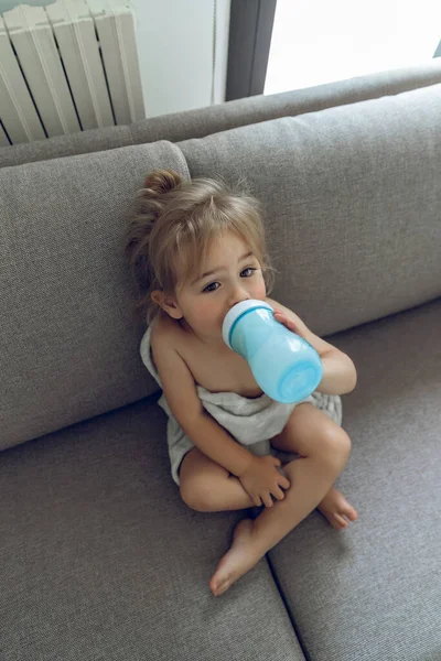 可爱可爱可爱的婴儿坐在家里的沙发上 与愉快的饮料配方奶 幼儿健康有机营养 — 图库照片