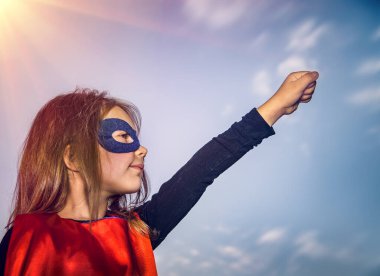 Supergirl gibi giyinmiş, el kaldırılmış güzel bir kızın profil fotoğrafı. Mutlu Neşe Zamanı. Feminizm ve Kadın Haklarının Kavramsal Fotoğrafı.