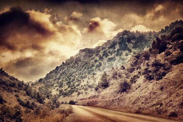 Grunge photo of road in the mountains — Stock Photo, Image