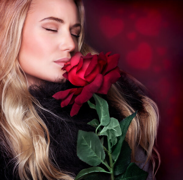 Beautiful woman smelling rose