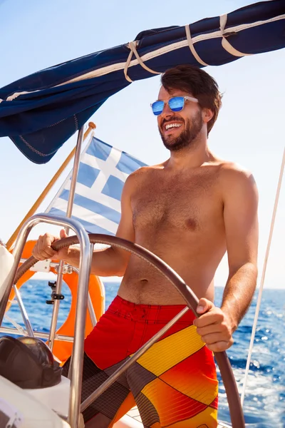 Happy guy behind wheel of sailboat — Stock Photo, Image