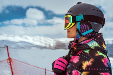 Lübnan 'ın karlı dağlarında kask ve renkli kayak gözlüğü takan kendine güvenen bir kadın snowboardcunun yakın portresi. Dağ kayak merkezindeki kış sporları görüntüsü. Aktif sporcu insanlar.
