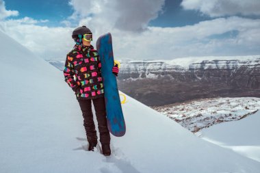 Karlı bir dağ sırtında elinde snowboard 'uyla duran bir kadın snowboardcunun tüm vücudu. Lübnan 'da kayak tatili, seyahat ve kış sporları için ideal..