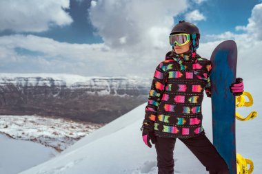 Karlı bir dağ sırtında elinde snowboard 'uyla duran bir kadın snowboardcunun tüm vücudu. Lübnan 'da kayak tatili, seyahat ve kış sporları için ideal..