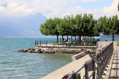 Brunnen, İsviçre - 02 Eylül 2020: Lucerne Gölü boyunca uzanan ve kıyı boyunca uzanan bir korkuluk ve ağaçlar var. Ayrıca burada insanları rahatlatan insanlar da var..