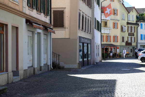 Fluelen, Switzerland - August 25, 2020: Residential buildings on the cobbled town street. Now there is no traffic on the road.