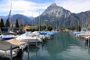 Fluelen, İsviçre - 25 Ağustos 2020: Birçok tekne Lucerne Gölü 'ndeki marinaya demirlemiştir. Arka planda bir dizi dağlık alan var..