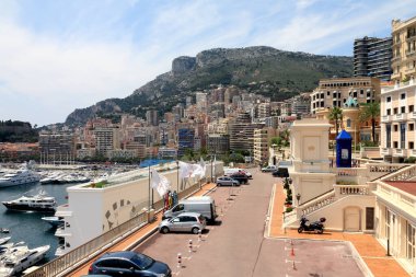Monte-Carlo, Monaco - Haziran 06, 2009: Yoğun kentsel gelişim bir şehir sokağı ile büyük marinadan ayrılmıştır. Arka planda tepeler var.