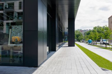 Varşova, Polonya - 19 Temmuz 2021: Powisle bölgesinin yeni modernize edilmiş bir bölgesinde modern bir binanın yakınındaki kaldırım. Bu binanın ön yüzünü oluşturmak için kullanılan modern materyalleri görebilirsiniz..