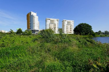 Varşova, Polonya - 3 Eylül 2021: Birçok ailenin Przyczolek Grochowski yerleşim bölgesinde bulunduğu apartman blokları göl kenarındaki ağaçlar ve bitkiler arasında yer alıyor ve Goclaw 'dan görülebiliyor