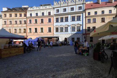 Lublin, Polonya - 10 Eylül 2021: Çevresindeki açık pazar tezgahları asfalt yol üzerinde bulunan eski kasaba binaları. Zamanını boşa harcayan ve bölgeyi ziyaret eden insanlar var..