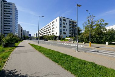 Varşova, Polonya - 3 Eylül 2021: Pek çok ailenin yaşadığı Goclaw semtindeki modern apartman binaları güneşli bir günde ağaçlar ve bitkiler arasında görülebilir