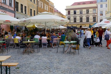 Lublin, Polonya - 10 Eylül 2021: Asfalt kaldırım üzerinde yer alan açık hava restoranları olan eski kasaba binaları. İnsanlar zamanlarını bölgeyi ziyaret ederek geçiriyorlar..