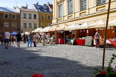 Lublin, Polonya - 11 Eylül 2021: Tedarikçilerin tezgahları eski kasaba meydanındaki binalardan birinin yanına dizilmişti. Asfalt kaldırımda ilginç bir yeri ziyaret eden insanlar var.