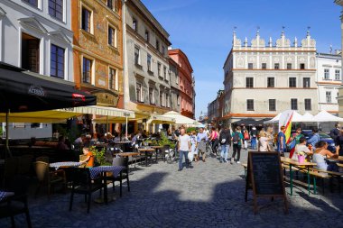 Lublin, Polonya - 10 Eylül 2021: Çevresindeki açık hava restoranları ve kafeleri asfalt yol üzerinde bulunan eski kasaba binaları. Zamanını boşa harcayan ve bölgeyi ziyaret eden insanlar var..